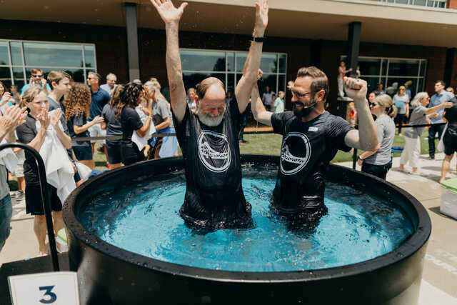 older man with arms in the air celebrating his baptism