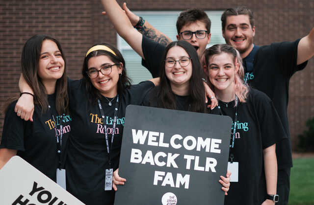 college kids smiling together with tlr signs