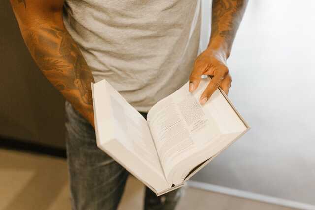 Image of tattooed man holding open Bible