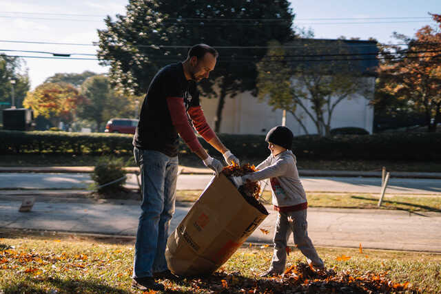 father and son cleaning up leaves at a be rich service project