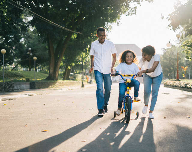 Image of parents teaching child to ride a bike
